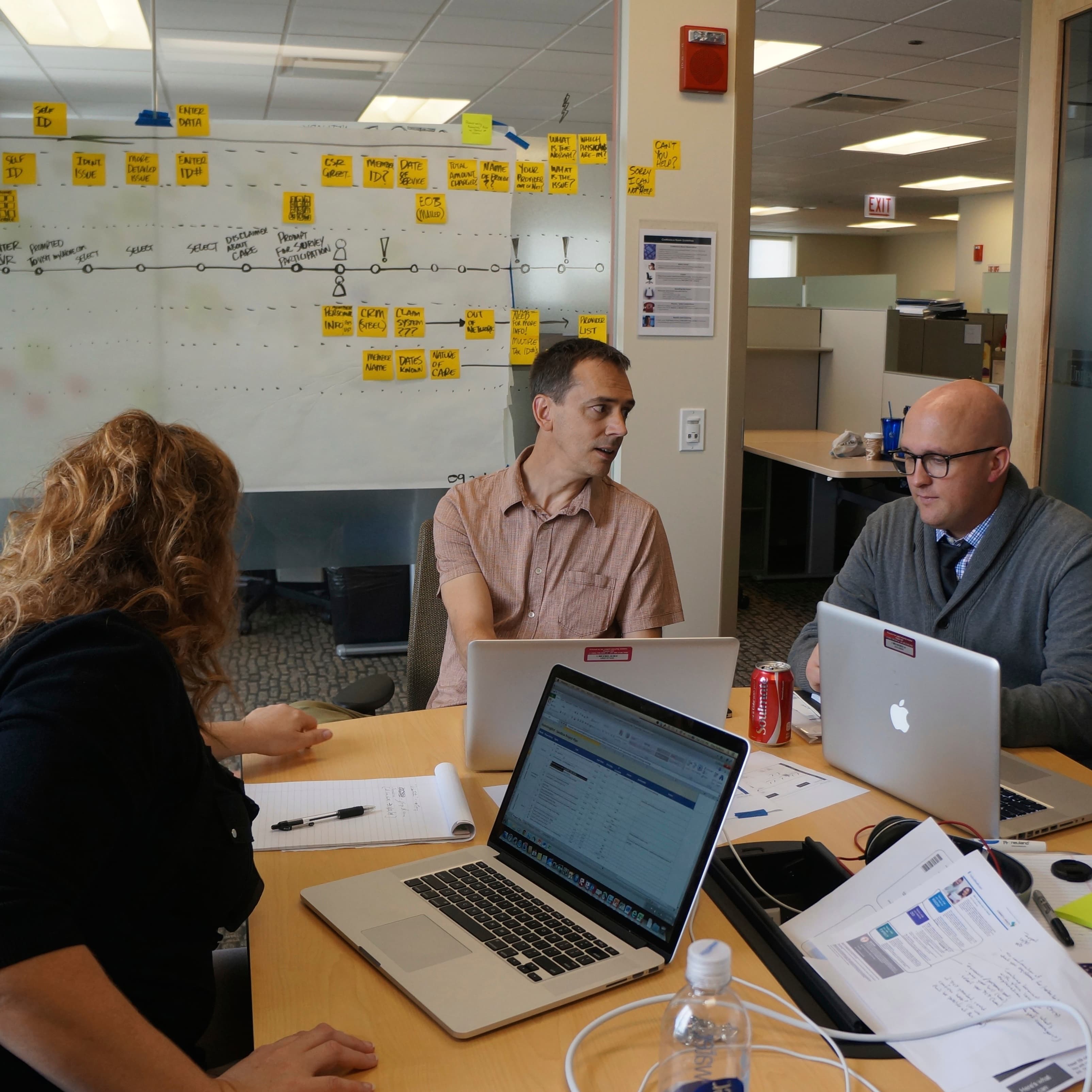 three team members collaborating in a conference room working on a service blueprint.